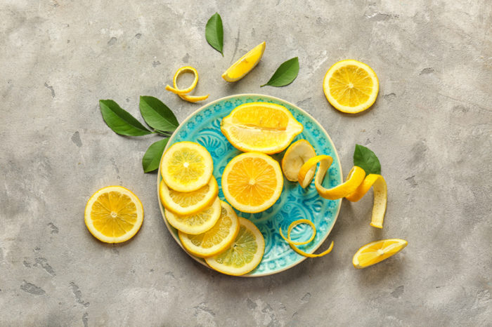 Skivade och delade citroner på ett blått fat. Vid sidan av fatet ligger även några gröna blad.